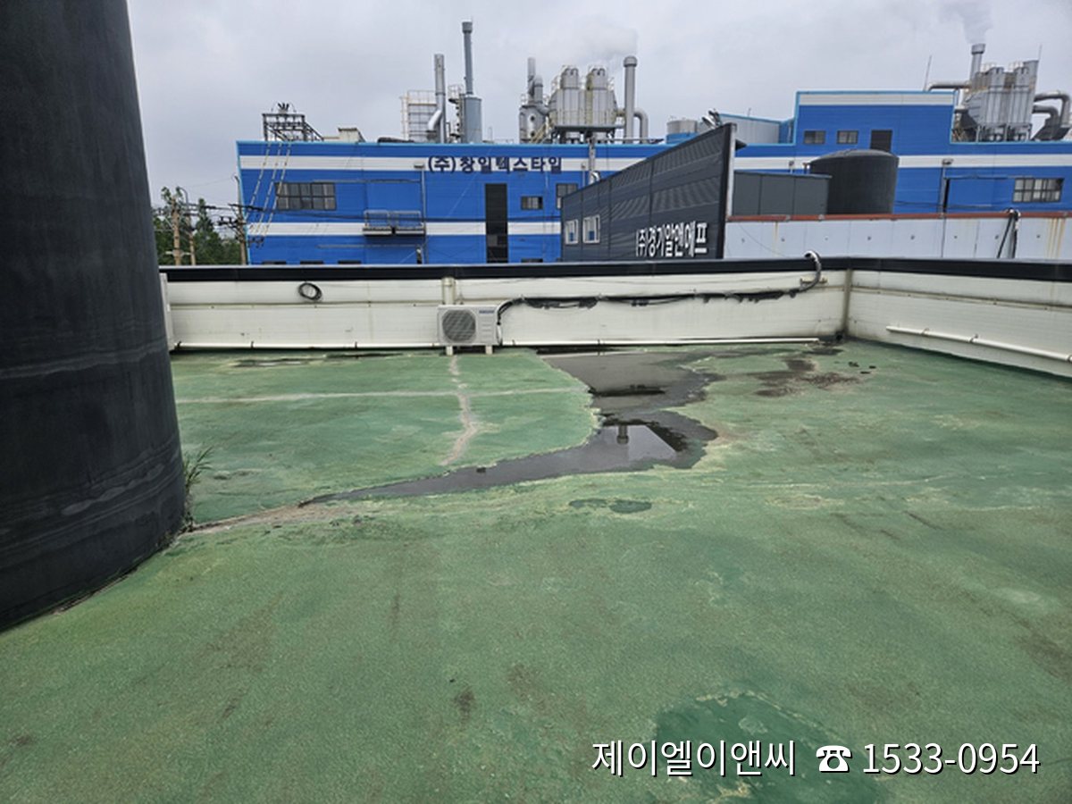 비가 그친 뒤에도 물자국과 얼룩이 남아 있는 공장 옥상 노후 방수층